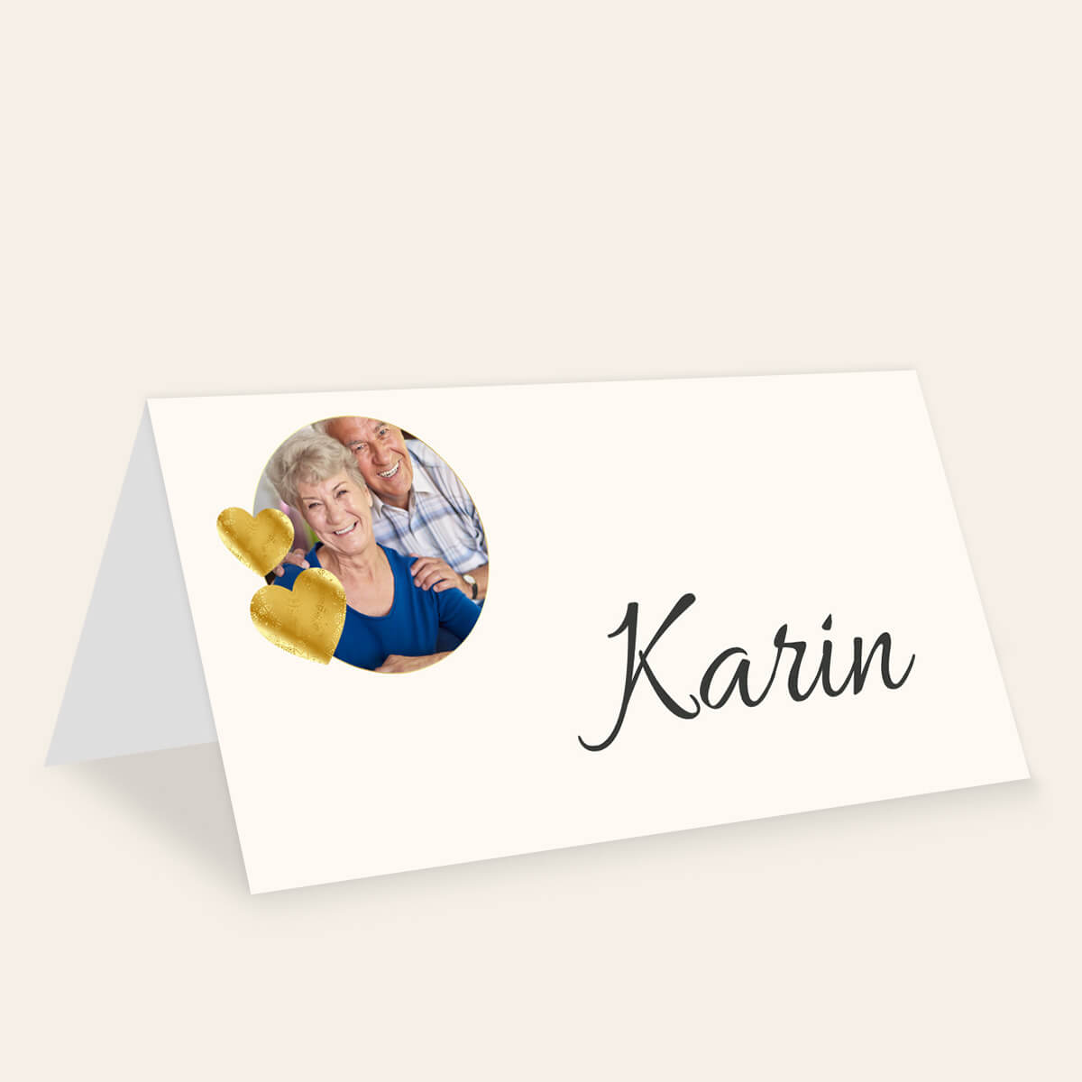 Cremefarbene Tischkarte Herzportrait mit einem Paarfoto, zwei goldfarbenen Herzen und dem Beispielnamen Karin