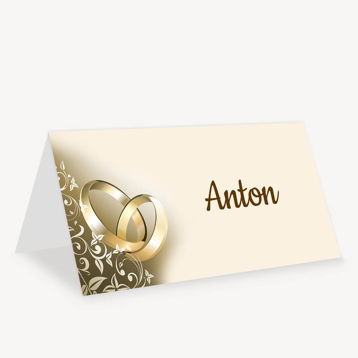Cremefarbene Tischkarte Ringpoesie mit goldfarbenen Eheringen, weißen Ranken und dem Beispielnamen Anton
